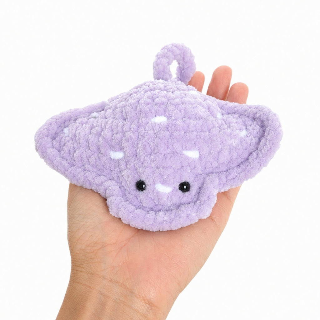 Crochet baby stingray plush shown resting in a hand to display real size, soft handmade amigurumi ocean toy with cute face and plush texture