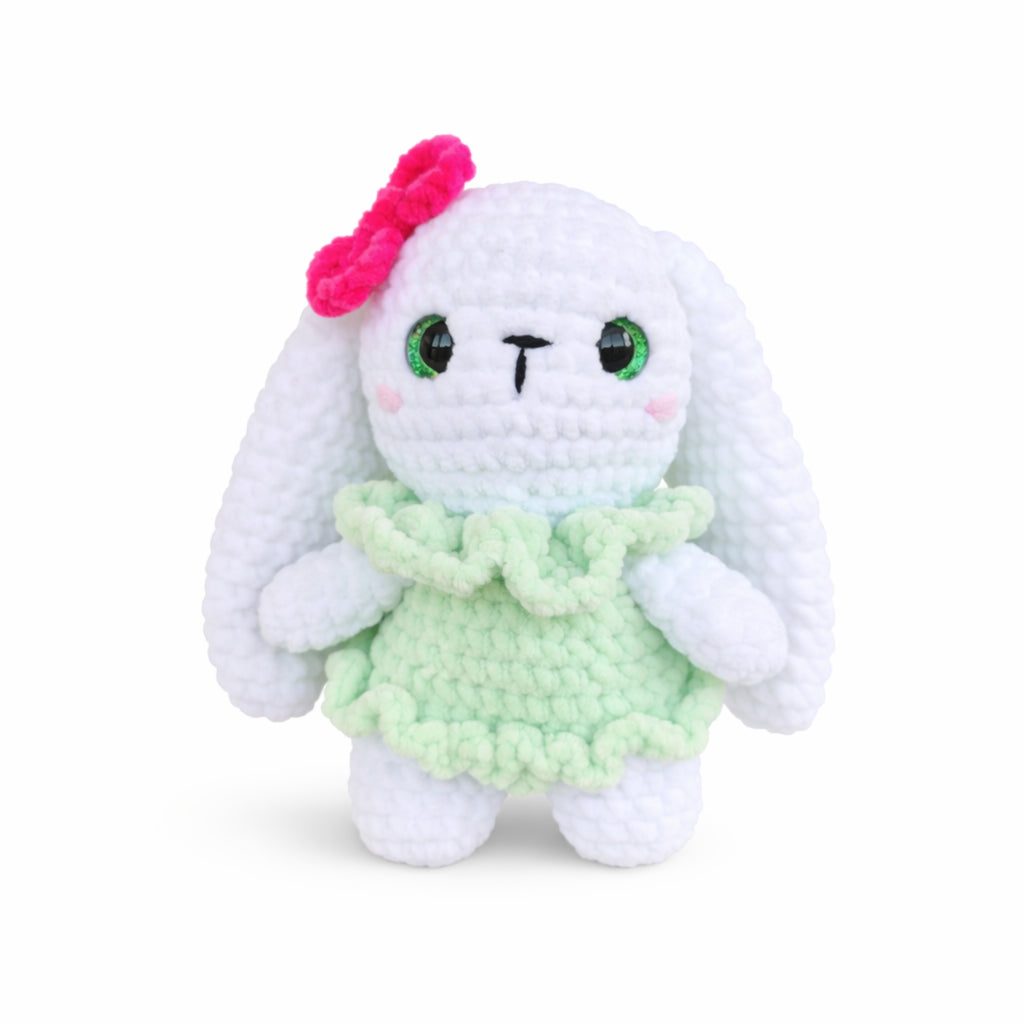 Handmade crochet bunny plush wearing a green dress with pink bow, cute amigurumi rabbit doll.