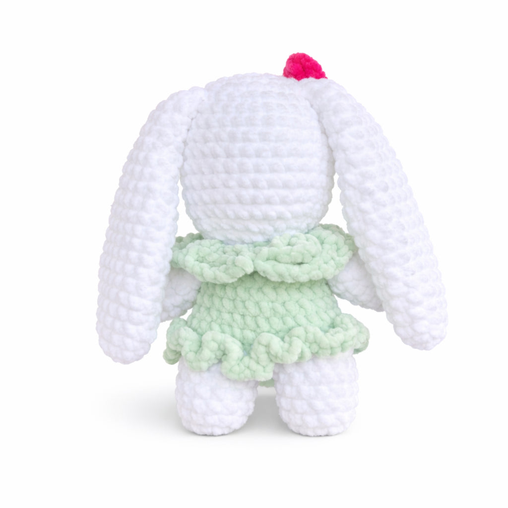 Back view of handmade crochet bunny plush wearing a green dress.