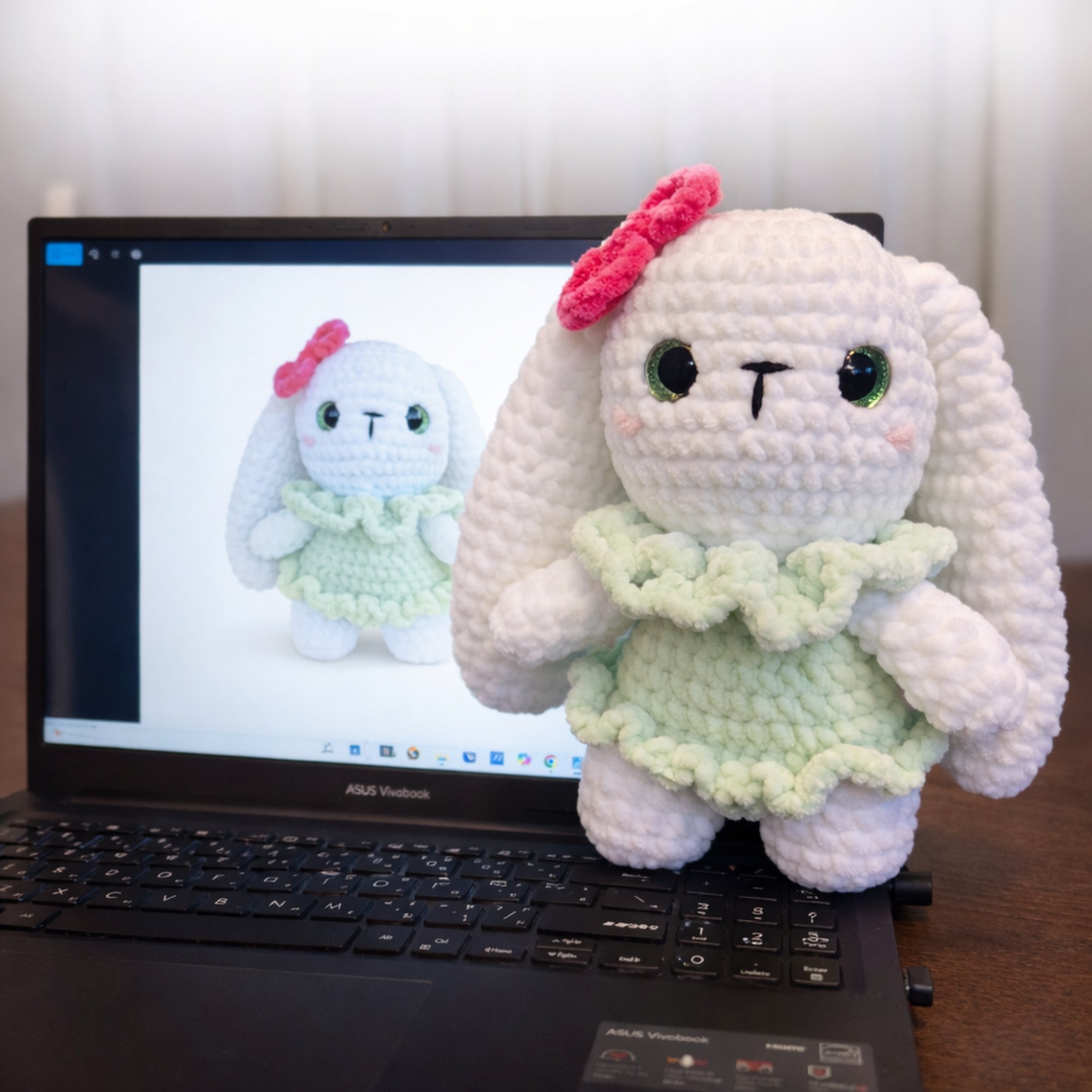 Handmade crochet bunny plush displayed next to a laptop for size comparison.