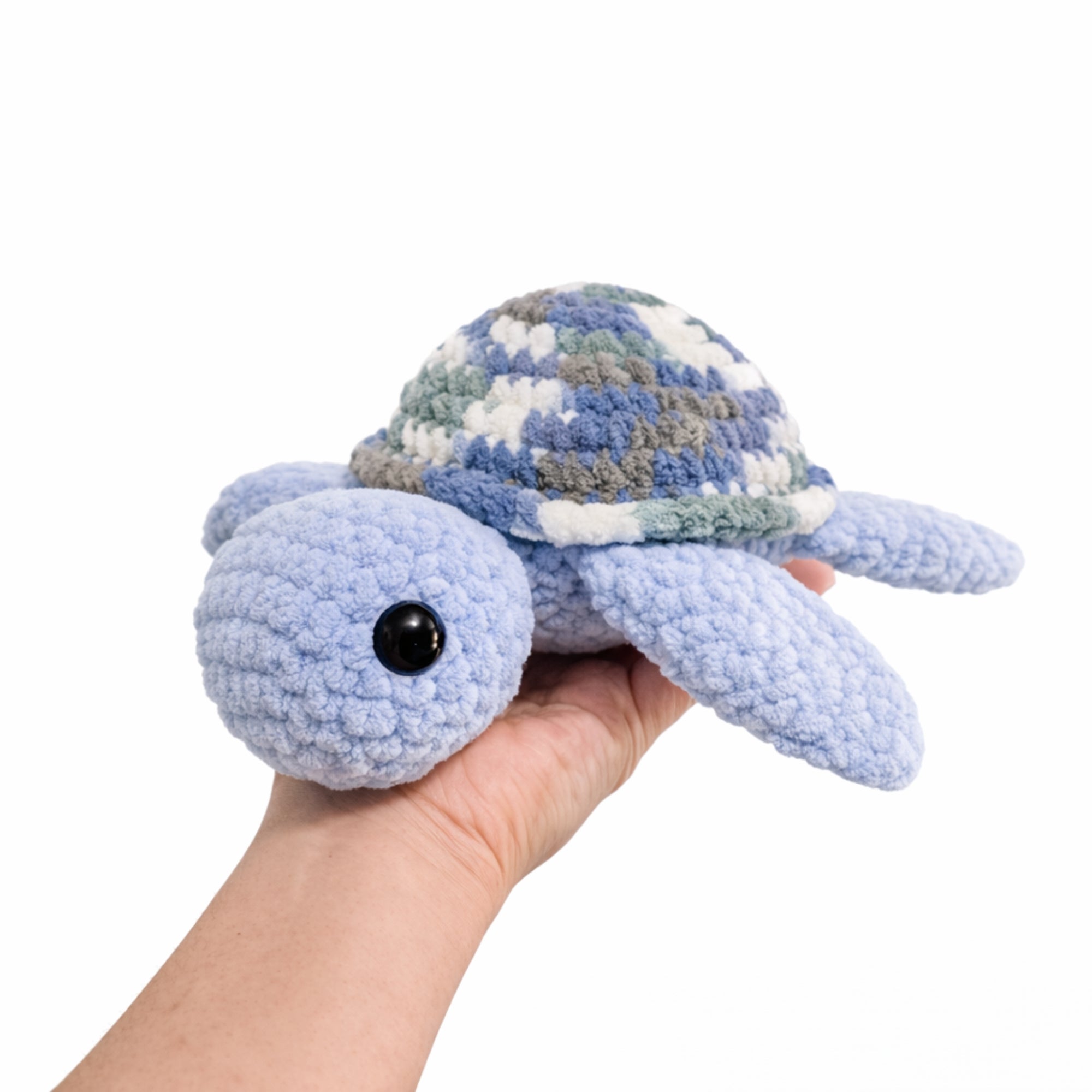 Hand holding handmade crochet turtle plush to show size, soft amigurumi stuffed toy.