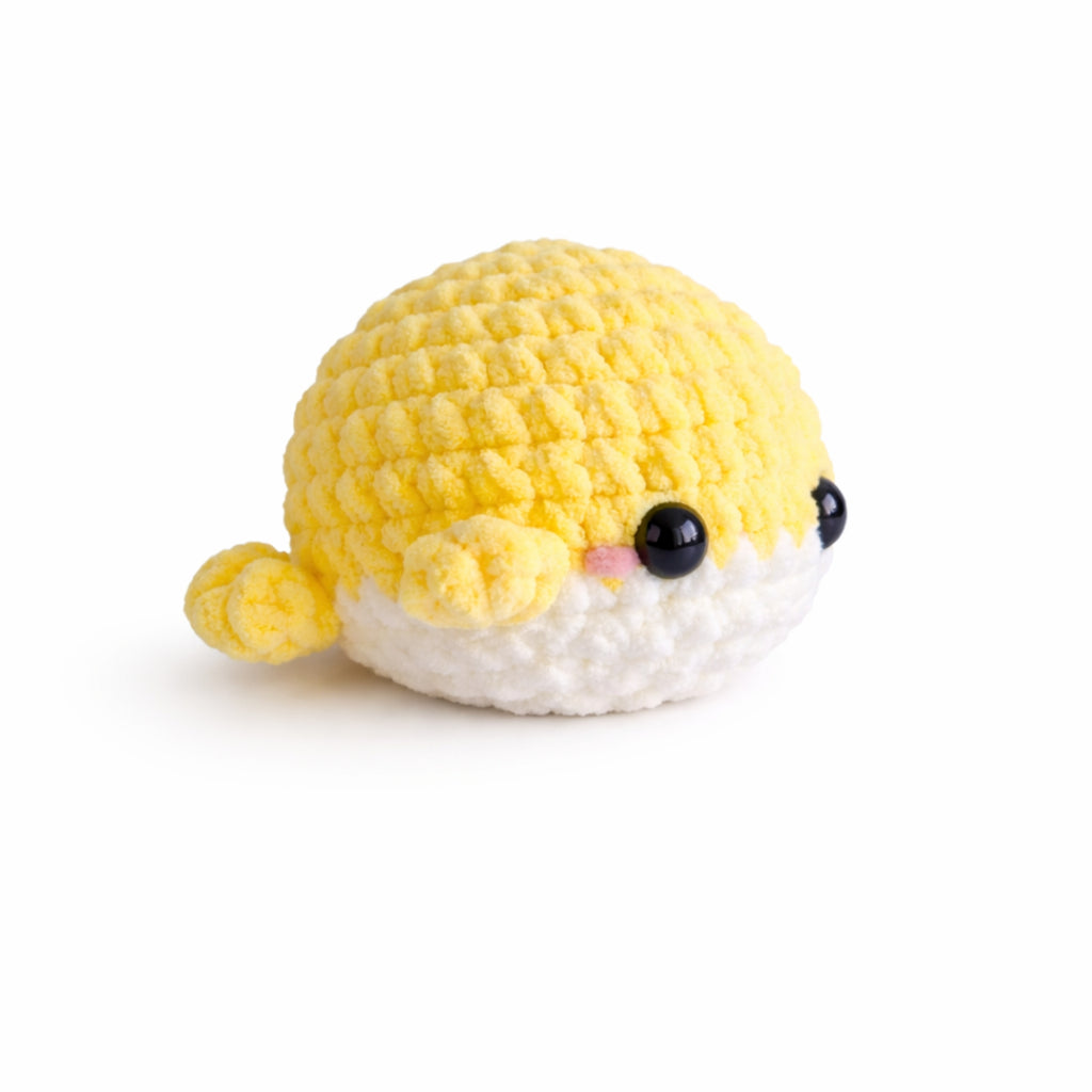 Side view of handmade crochet baby whale amigurumi plush in yellow chenille yarn showing body and tail