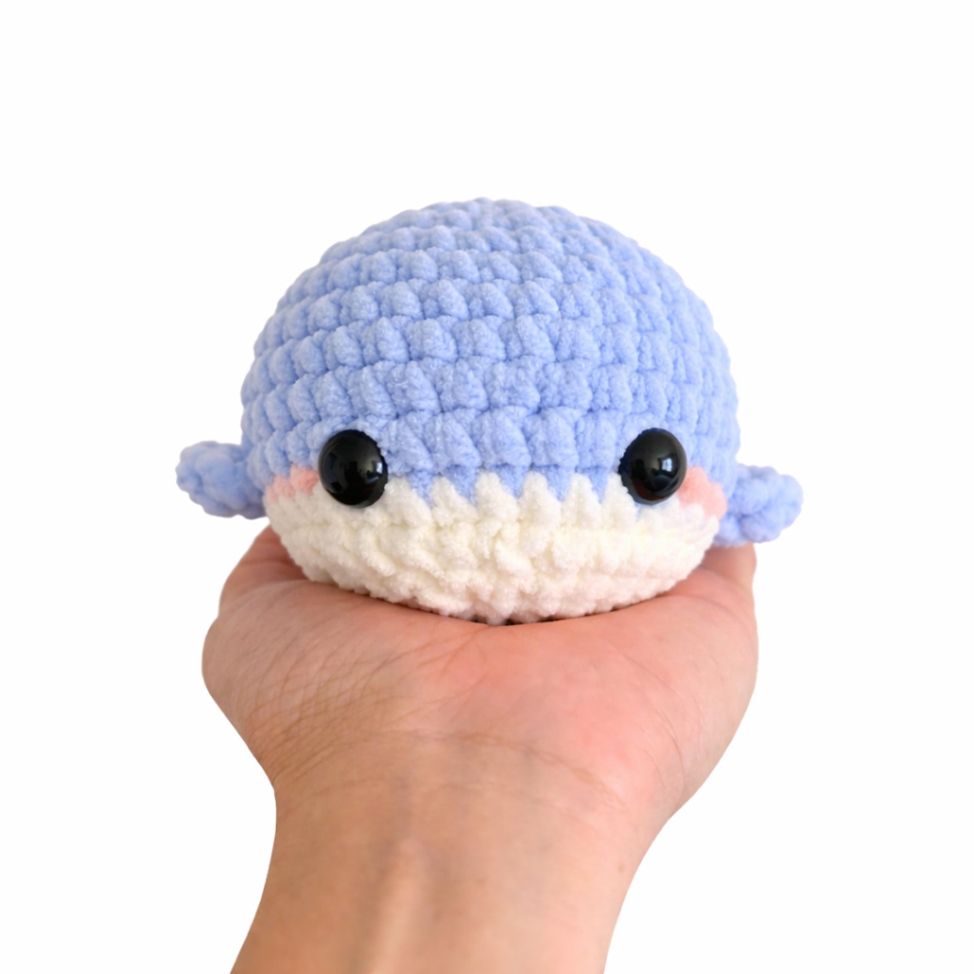Handmade crochet baby whale amigurumi plush shown in hand to display palm size