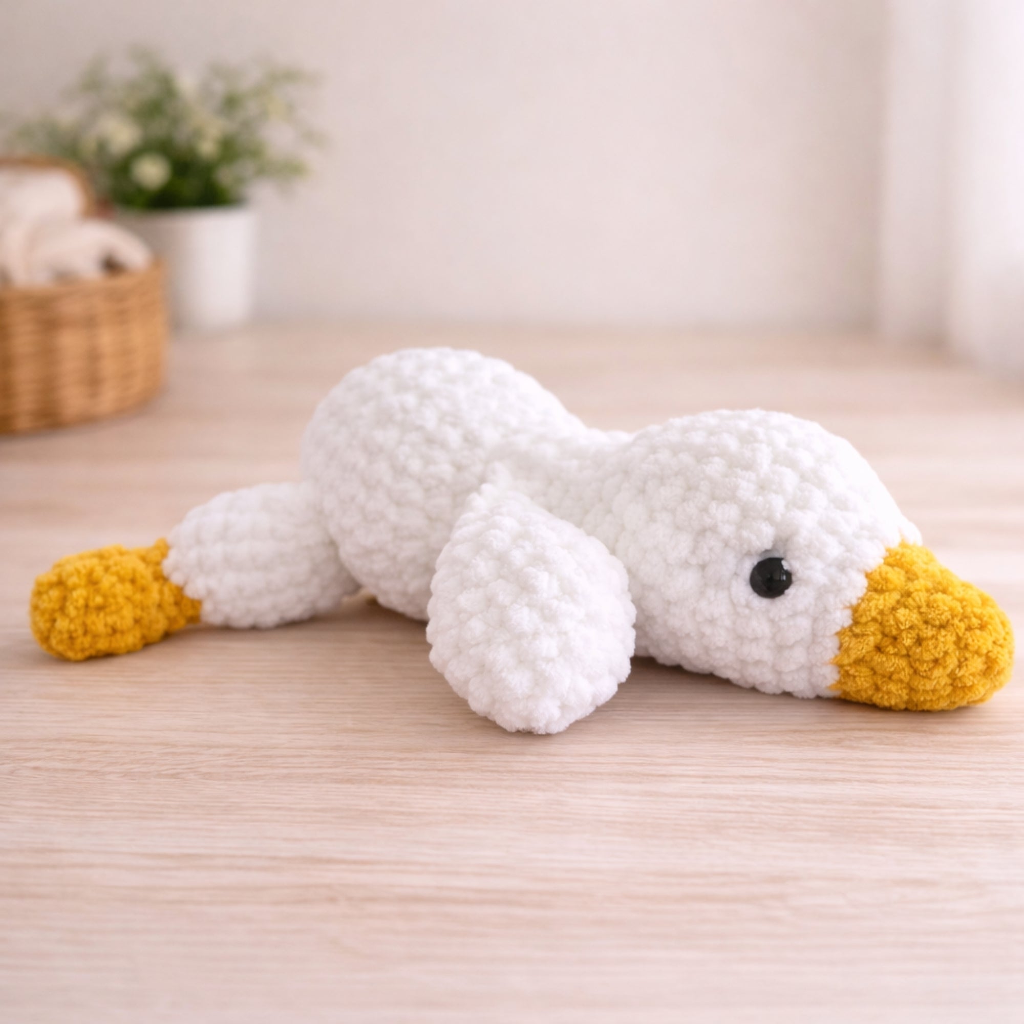 Handmade crochet goose amigurumi plush toy displayed on wooden table with cozy home decor background