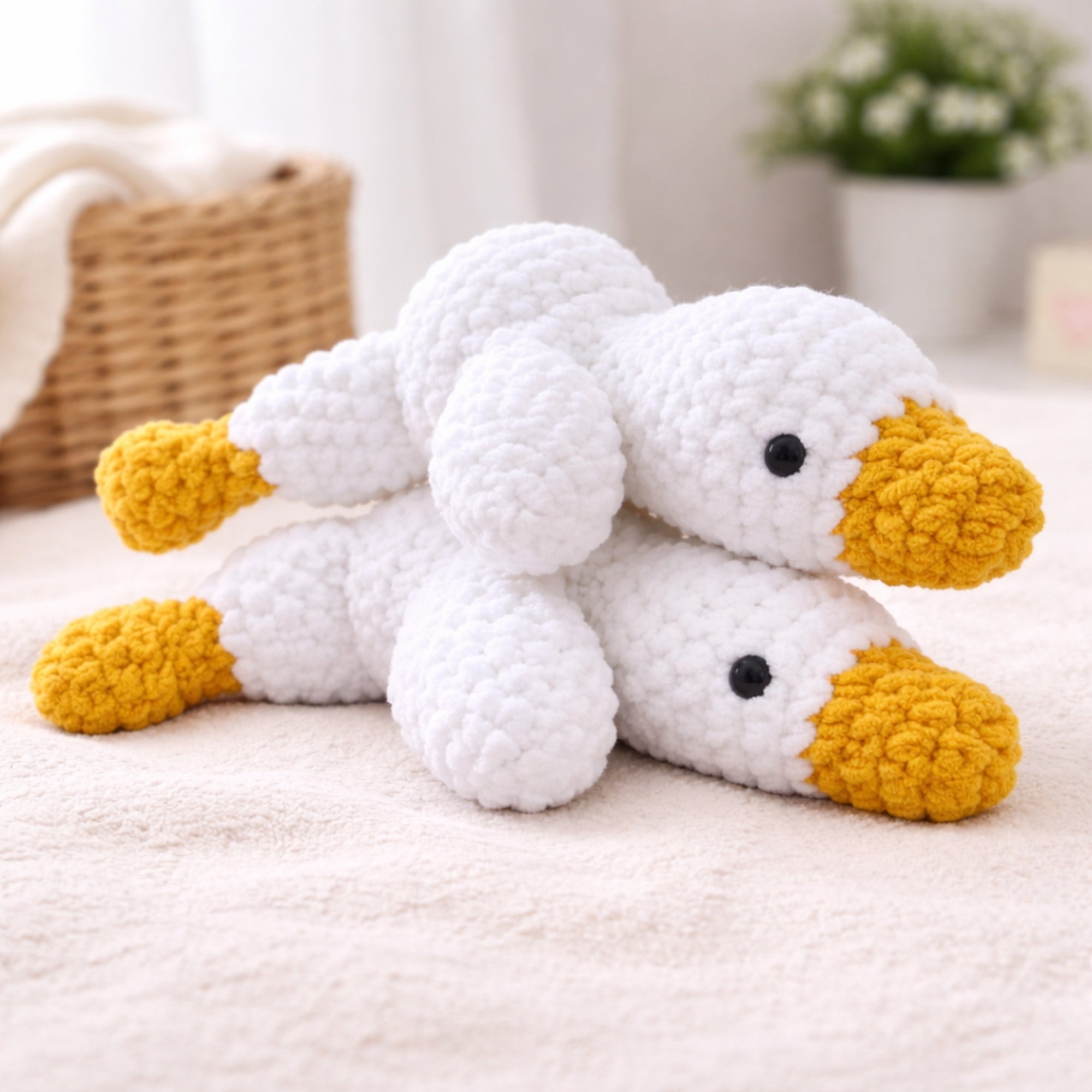 Two handmade crochet goose amigurumi plush toys on soft blanket in cozy home decor setting