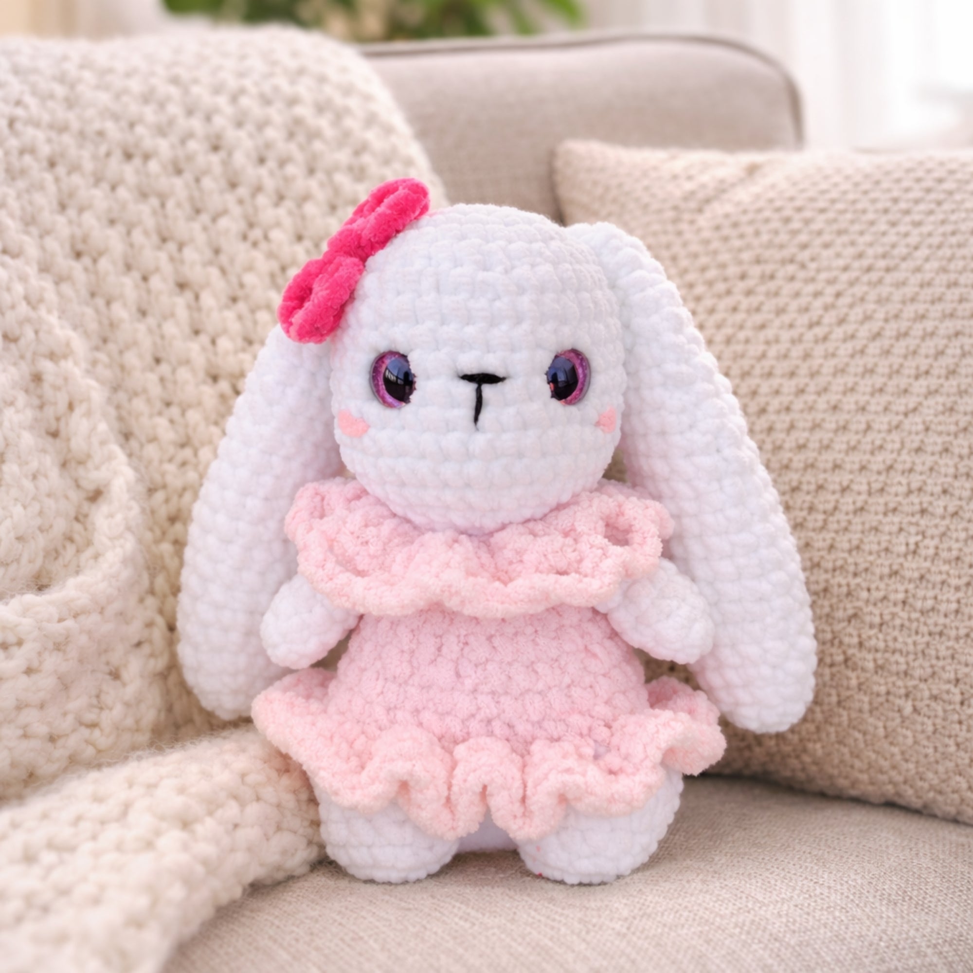 Handmade kawaii crochet bunny plush in pink dress sitting on chair