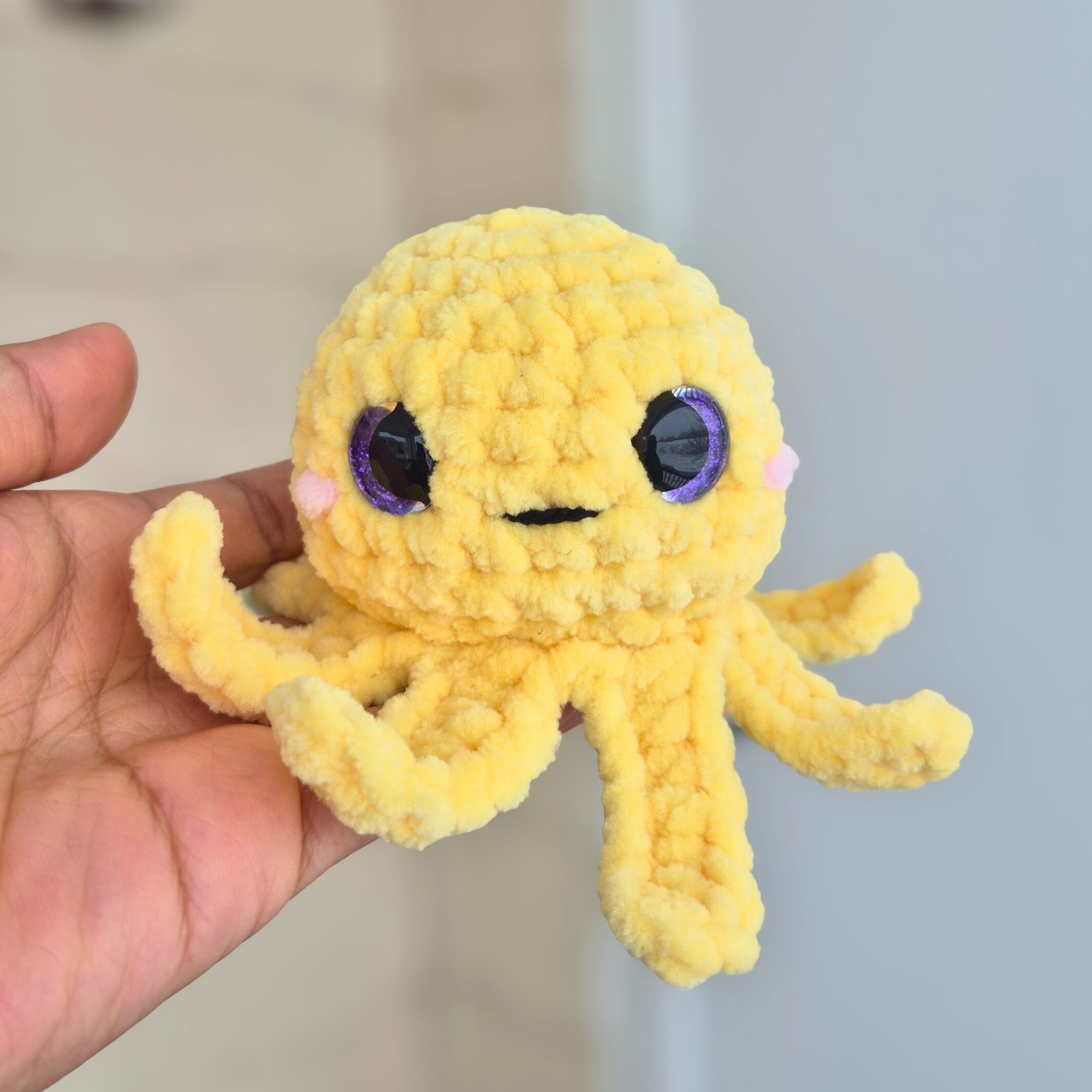 Small handmade crochet octopus plush toy shown in hand for size reference